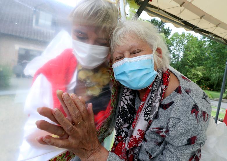 Lily Hendrickx, de 83 años, residente en el geriátrico belga 'Le Jardin de Picardie', disfruta de los abrazos y caricias que le da Marie-Christine Desoer, la directora del centro, a través de una pared hecha con láminas de plástico en Peruwelz.