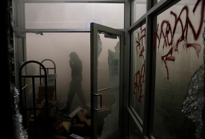 Un manifestante camina dentro de una tienda dañada.