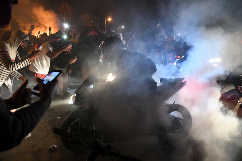 Los manifestantes aceleran los motores de sus motocicletas mientras otros filman cerca del tercer recinto de la policía de Minneapolis durante el tercer día de manifestaciones en respuesta a la muerte del hombre afroamericano George Floyd.