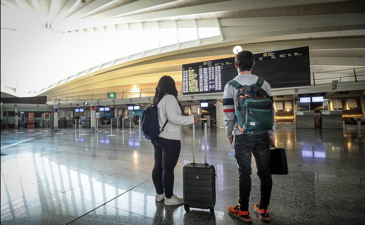 Dos pasajeros aguardan en facturación, en un aeropuerto de Loiu desierto.