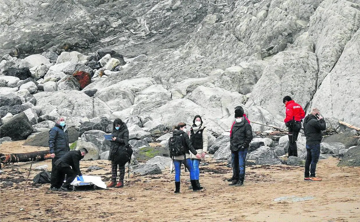 Ertzainas y miembros de la comitiva judicial recogen los restos humanos aparecidos en la playa de Arrigunaga. 