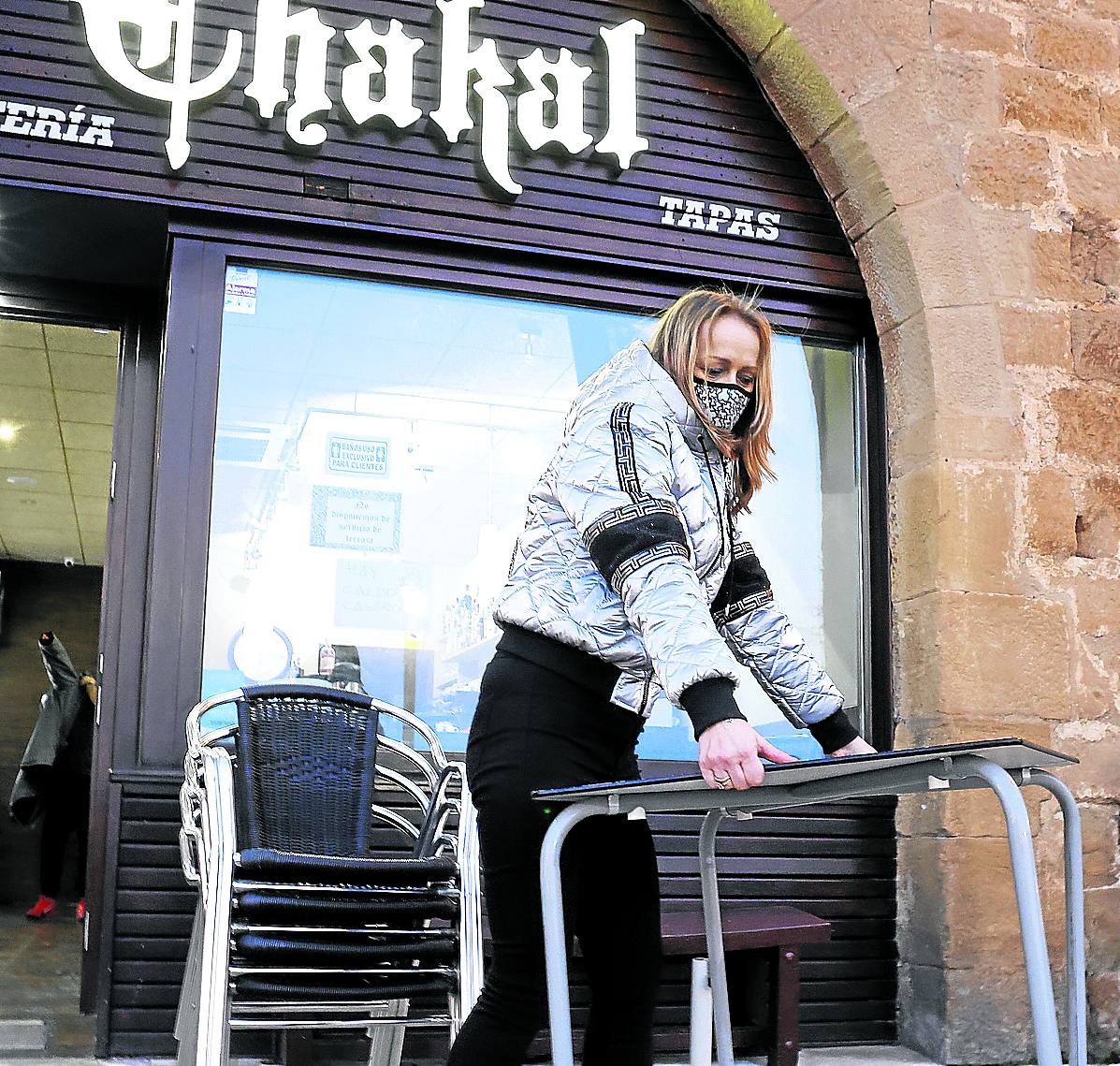 Una camarada del bar Chakal, en Laguardia, recoge la terraza antes del cierre. 