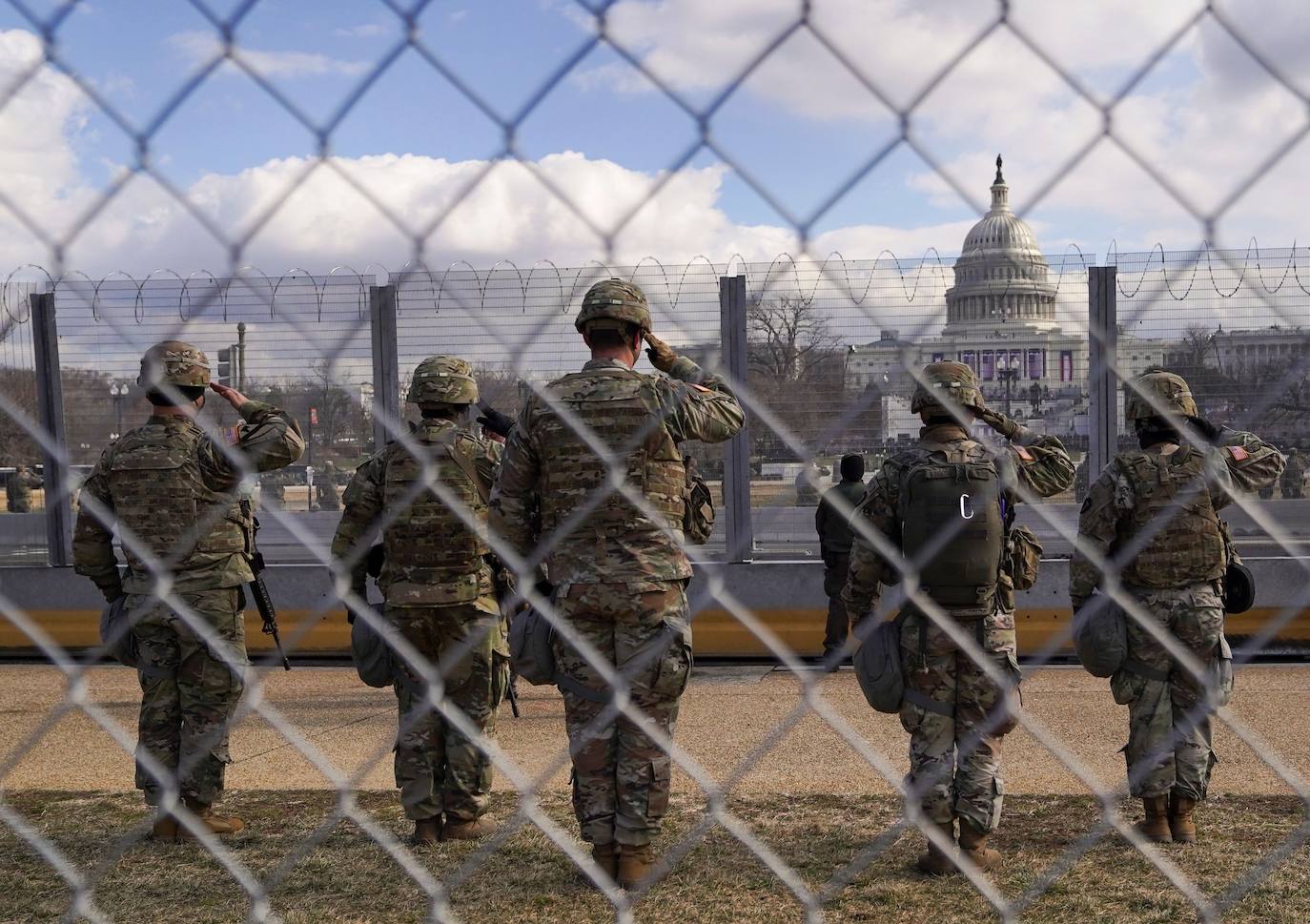 Los miembros de la Guardia Nacional saludan frente al edificio del Capitolio de los Estados Unidos.