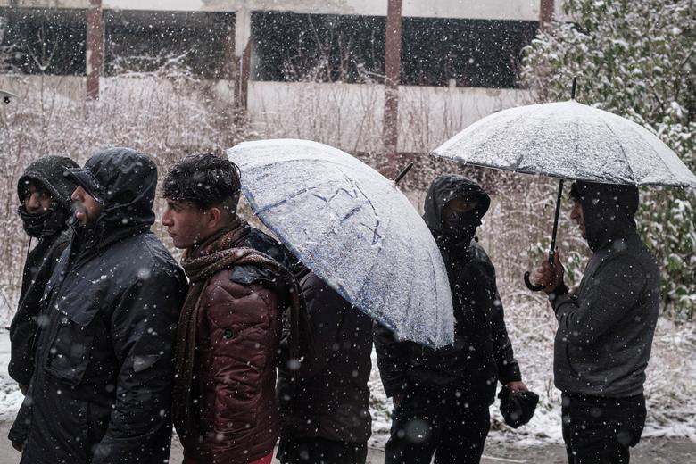 Los migrantes se paran frente a una fábrica abandonada mientras cientos de ellos se refugian en edificios abandonados.