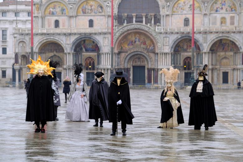 La gente usa máscaras y disfraces de carnaval en la Plaza de San Marcos para celebrar el carnaval anual de Venecia.