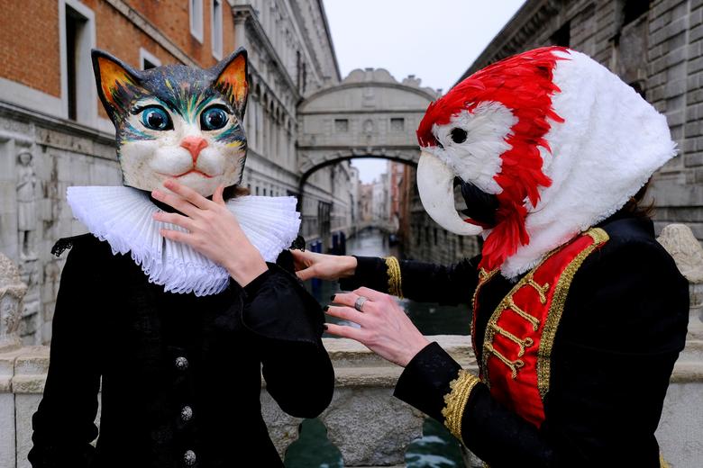 La gente usa máscaras de carnaval junto al Puente de los Suspiros para celebrar el carnaval anual de Venecia, que ha sido cancelado este año debido a la pandemia de coronavirus.