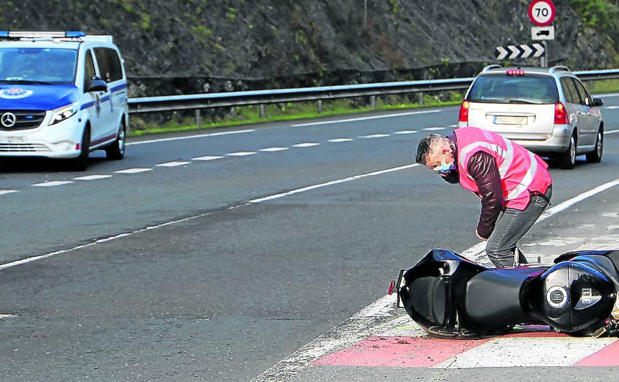 Un agente de la Ertzaintza inspecciona la motocicleta tras el accidente mortal.