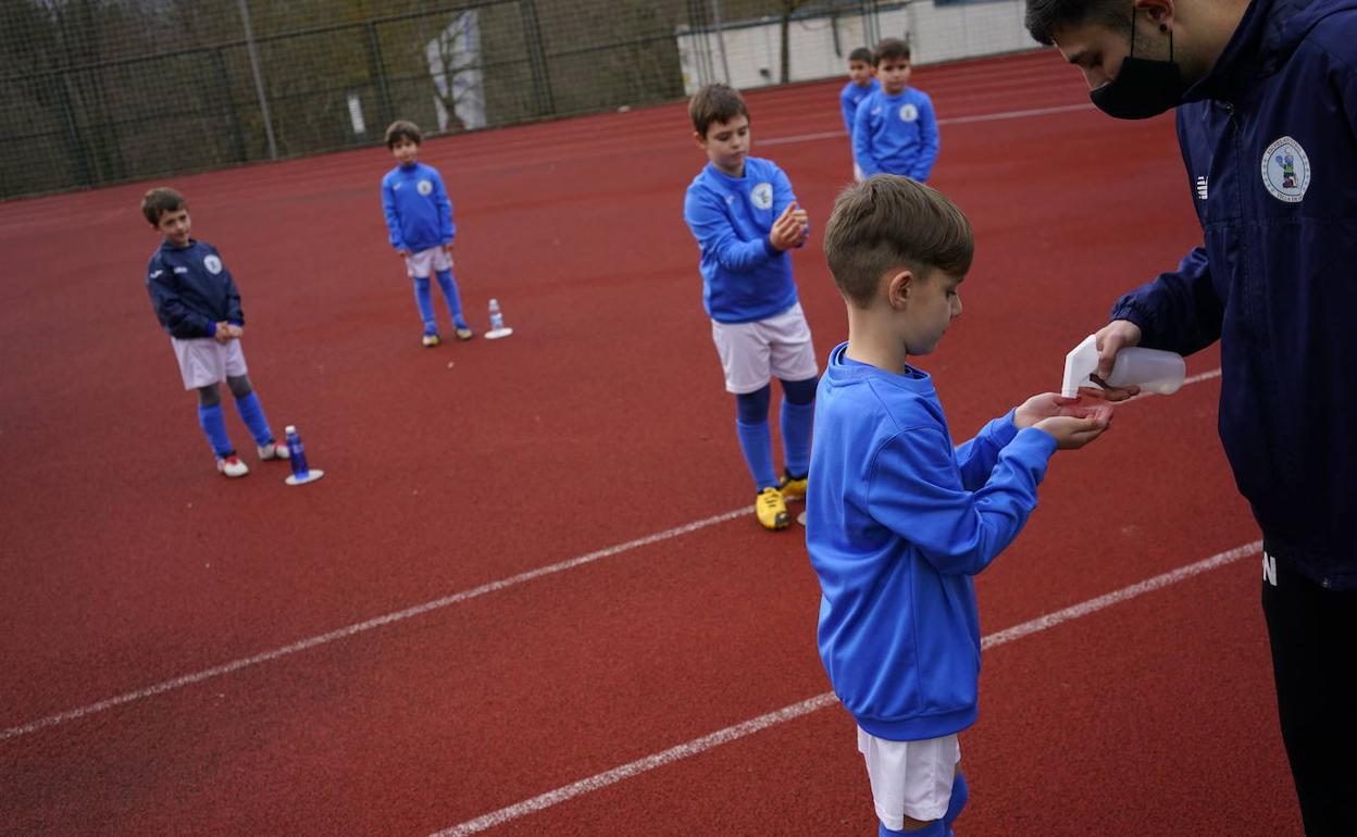 Un técnico proporciona gel desinfectante a uno de los chavales que entrenan en la escuela de fútbol de Ermua. 