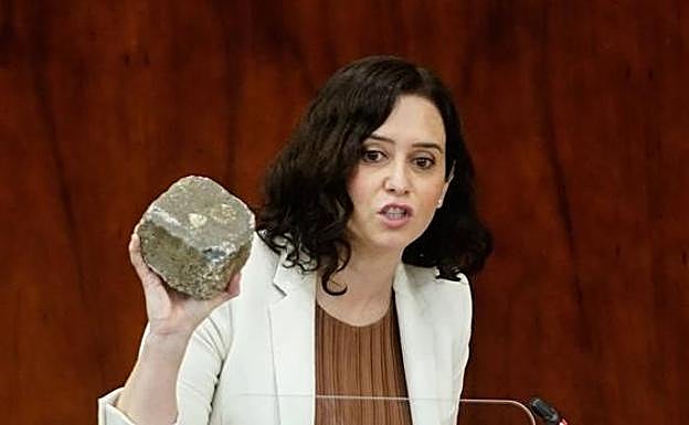 La presidenta de Madrid, Isabel Díaz-Ayuso, muestra un adoquín lanzado en la capital. EC 