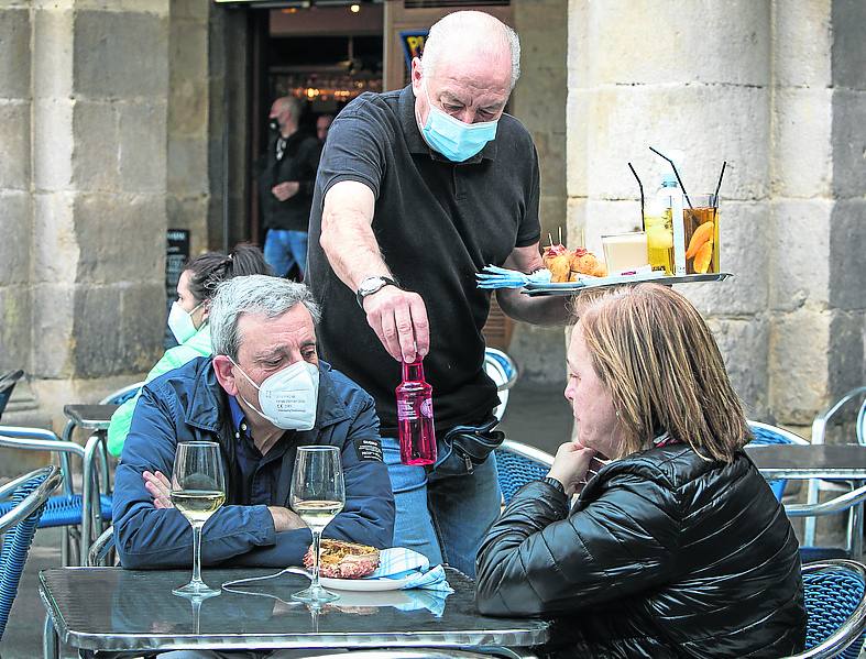 Una pareja de clientes recibe su consumición en la Plaza Nueva. 