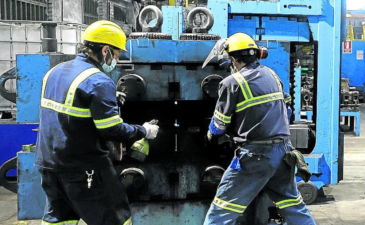 Dos operarios se emplean a fondo en una industria.