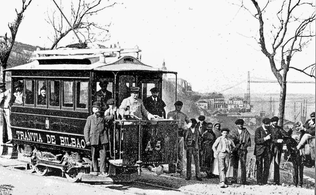 En Portugalete. Varios viajeros se bajan del tranvía con el Puente Colgante al fondo, inaugurado hacía tres años. 
