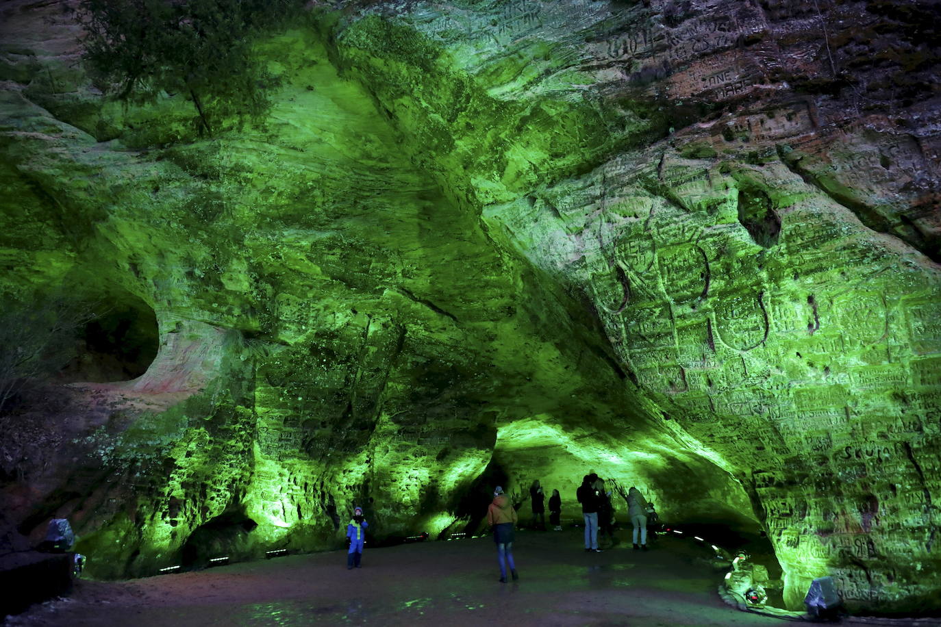 La gente visita la Cueva de Gutman que está iluminada en verde antes del Día de San Patricio en Sigulda, Letonia.