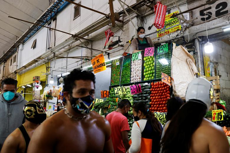 Una mujer mira como luchadoras de lucha libre, alienta a los mexicanos sin máscara a usar mascarillas como medida de prevención contra el coronavirus.