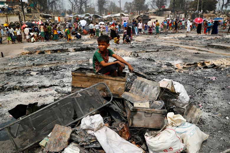 Un niño refugiado rohingya sentado sobre una pila de material quemado después de que estallara un incendio masivo en un campo de refugiados rohingya en Cox's Bazar, Bangladesh.