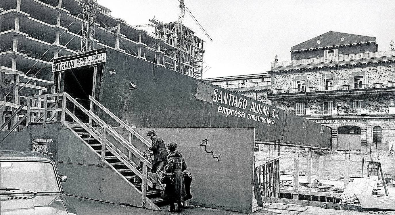 A la par que concluía en 1976 la construcción de la Residencia Sanitaria Ortiz de Zárate -después Hospital Txagorritxu y en la actualidad HUA- se ampliaba de nuevo el Hospital General Santiago Apóstol, en pleno centro de Vitoria, hasta entonces el referente de la sanidad pública en Álava. El crecimiento poblacional aconsejaba una mayor y mejor atención asistencial y en respuesta a la demanda se levantó a lo largo de 1977 el edificio que da a la calle La Paz, parecido en su concepción al bloque construido previamente en el ala este del complejo hospitalario. El proyecto de Ángel Esteban, encomendado a la constructora Santiago Aldama, constaba de dos sótanos, seis plantas y un ático. Bajo tierra se habilitaron la cocina, la lavandería, los talleres y otros servicios complementarios. El bajo y el primer piso se destinaron a consultas de especialidades médicas y los restantes, al ingreso de pacientes. Cada planta, entre la segunda y la quinta, disponía de 40 camas y se reservó la última a enfermos alcohólicos con trastornos psiquiátricos. Paralelamente se construyó una capilla en la esquina Olaguíbel-La Paz de culto abierto al vecindario sobre el solar de la anterior, derribada por entender que su estilo neoclásico desentonaba con el renovado hospital. La primitiva iglesia de Nuestra Señora de la Victoria databa de 1884 y fue obra de Pantaleón Iradier.