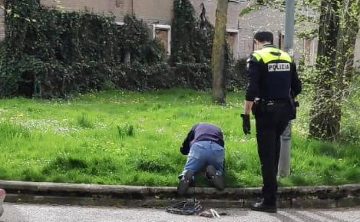 Un operario revisa el interior de una arqueta en la trasera de Avenida de Olárizu en compañía de un agente local. 