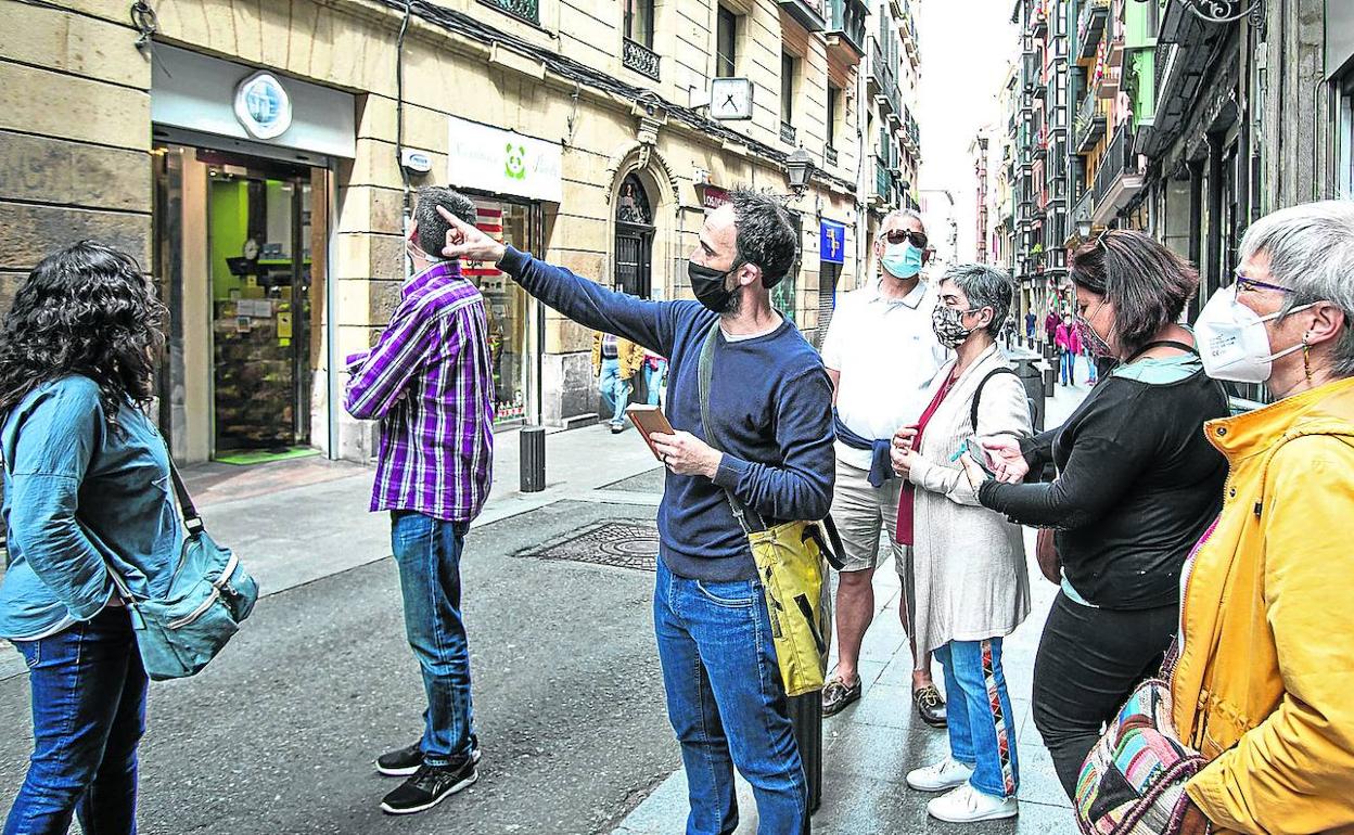 Un guía turístico muestra algunas curiosidades de la calle Askao a un grupo de visitantes locales. 