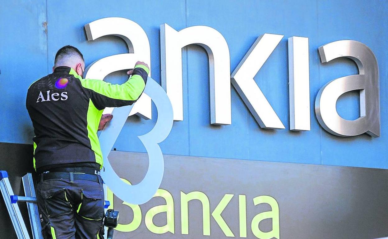 Un operario retira las letras de Bankia de una sucursal de Logroño, para colocar las de Caixabank.