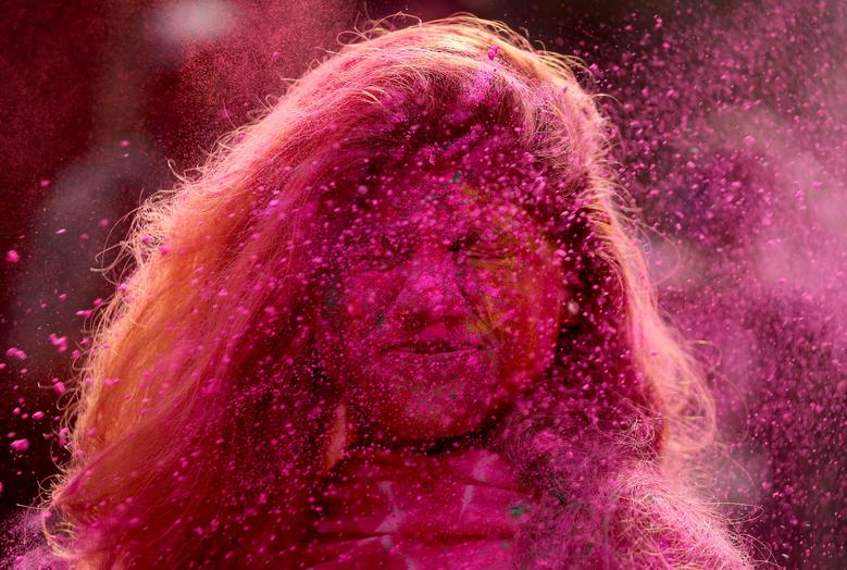 Una mujer embadurnada en colores reacciona cuando se le arroja polvo durante las celebraciones de Holi en Chennai, India.