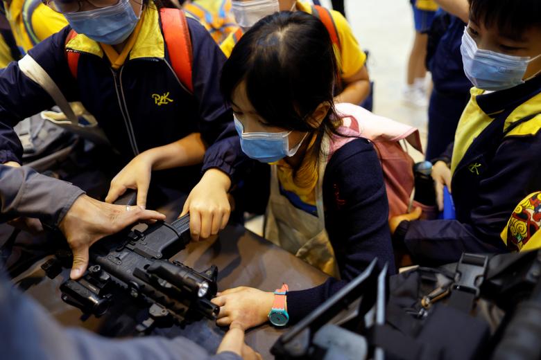 Los niños miran una metralleta de gas SIG Sauer MPX.