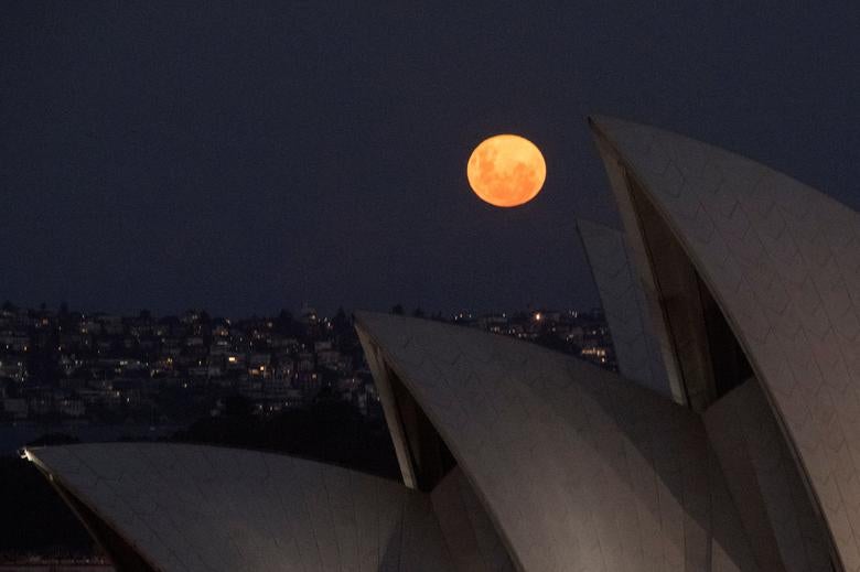 La primera superluna del año se levanta detrás de las velas de la Ópera de Sydney en Sydney, Australia. 