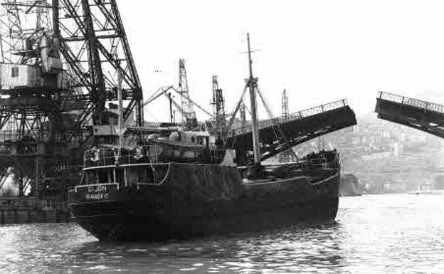 Un barco pasa por debajo de las hojas abiertas del puente de Deusto. 