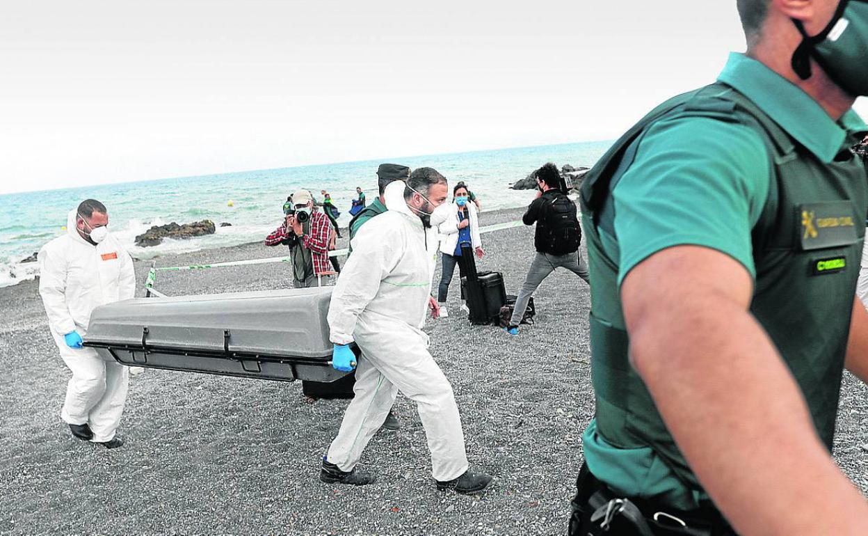 Trabajadores trasladan el cadáver de una de las personas que trató de llegar a Ceuta.