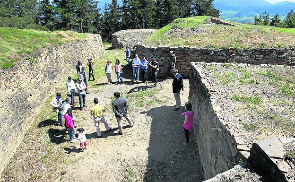 Un grupo de visitantes atiende las explicaciones en el Oppidum de Arrola. 