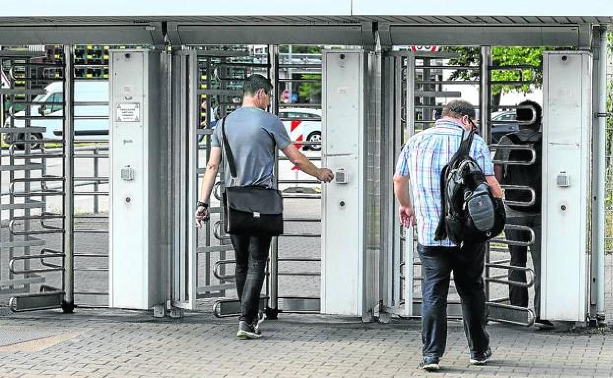 Trabajadores atraviesan los tornos de salida de una empresa industrial. 