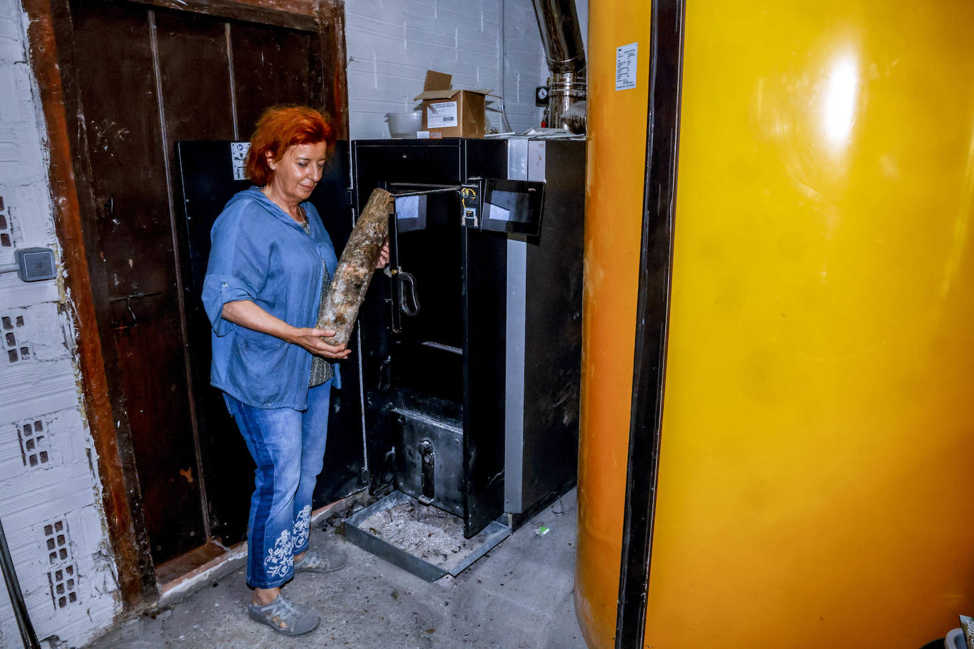 Ana alimenta la caldera de biomasa con leña.
