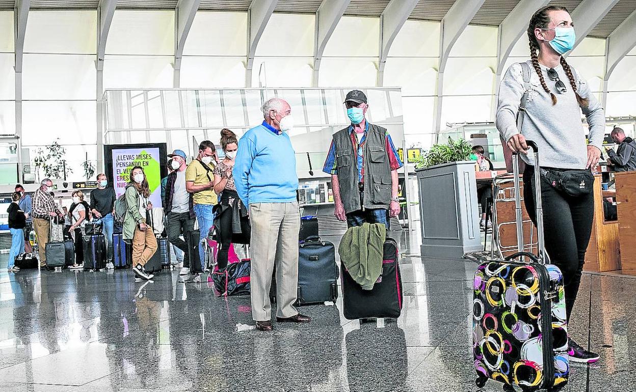 Pasajeros hacen cola en la terminal para facturar sus maletas. 