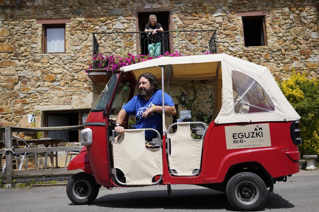 Rober Iriondo posa en su vehículo frente al Eguzki B&B, mientras Sally Christopher observa desde el balcón. 