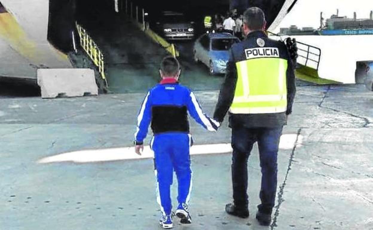 Un policía nacional acompaña a un menor. 