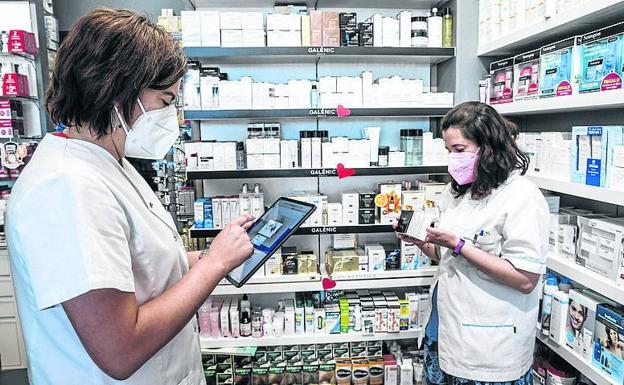 Laura García, en primer término, con la tablet en su farmacia de Labastida.