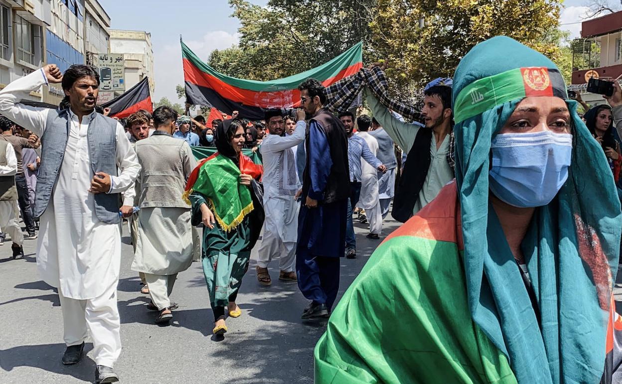 Protestas. Afganos muestran en una calle de Kabul banderas del anterior Gobierno.