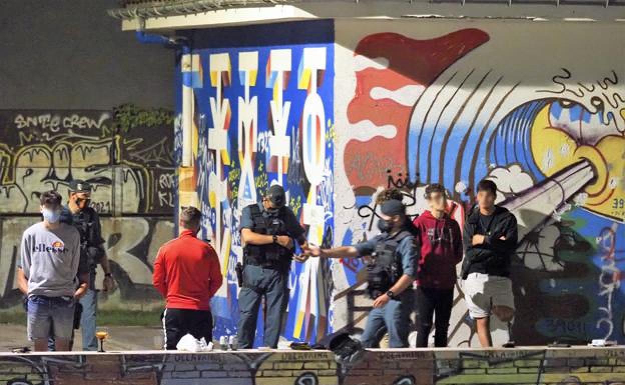 Tres agentes de la Usecic de la Guardia Civil de Cantabria revisan la documentación de un grupo de jóvenes junto a la playa de Ris.