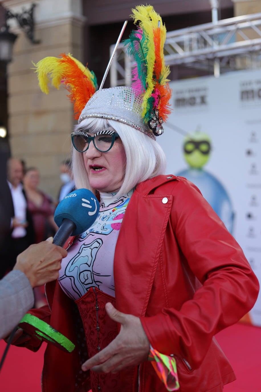 Yogurinha, el personaje creado por las Fellini en 1994 y que se convirtió en símbolo de la libertad sexual, le puso color a la alfombra roja con un diseño de su propia firma, un corsé rojo y una chupa de cuero del mismo color. Además incluyó un tocado de plumas multicolor.