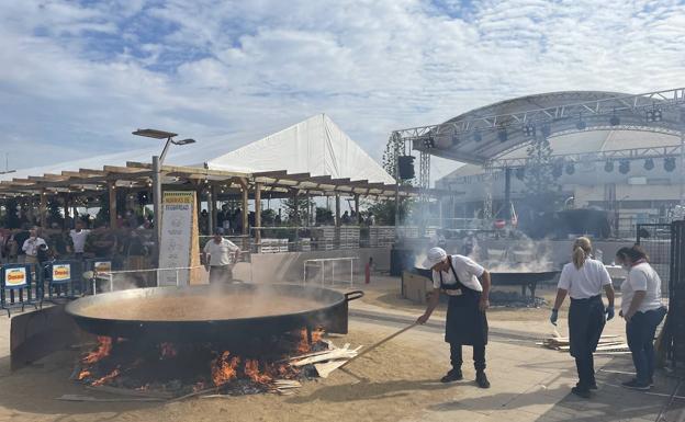 Cocineros preparan la comida en dos grandes paelleras a la entrada del centro de eventos. 