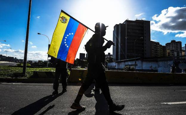 Una persona porta la bandera de Venezuela en las calles del país. 