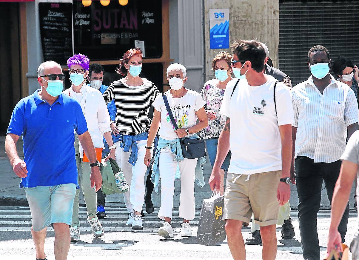 Varias personas caminan por Bilbao con la mascarilla puesta.