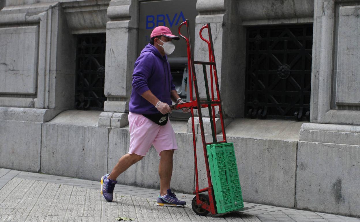 Un trabajador inmigrante conduce su carretilla de reparto por una calle de Bilbao. 