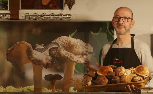 Juan Andrés Román en la barra del Bar Lagunak (Galdakao) con una cesta de hongos negros y pinícolas.