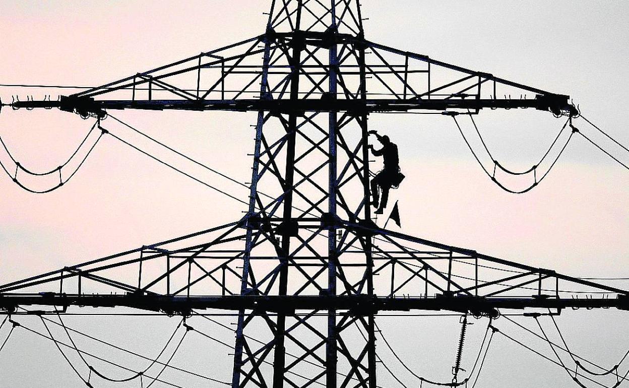 Un operario trabaja en una torre de alta tensión.