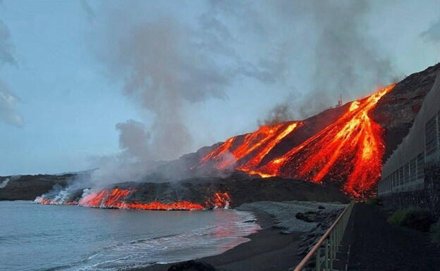 Vista de las cascadas de lava al caer al mar en la playa de Los Guirres. 