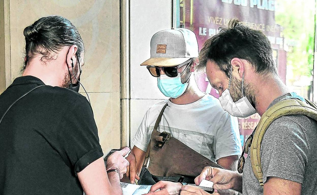 Turistas enseñan el pasaporte covid para entrar en un cine de París. 
