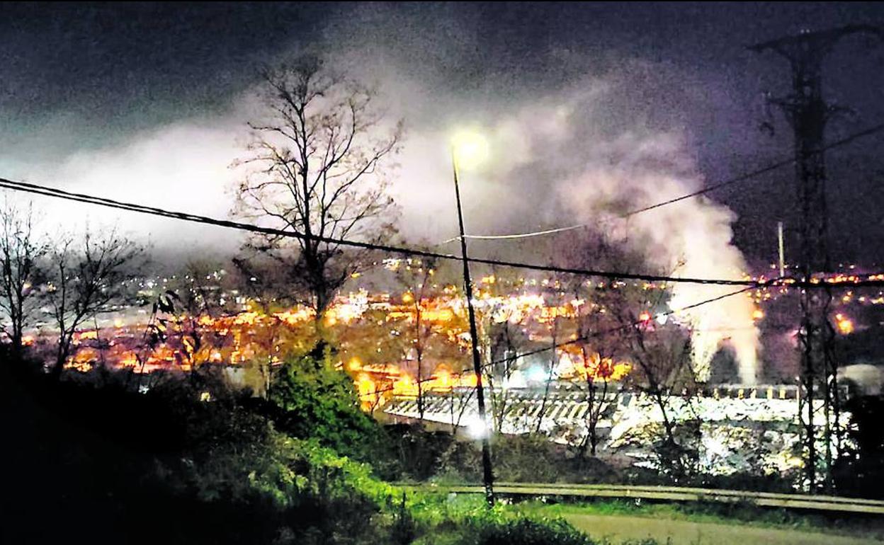 Imagen nocturna del barrio de Asua, en el municipio de Erandio, sobre el que sobrevuela el humo de una empresa.