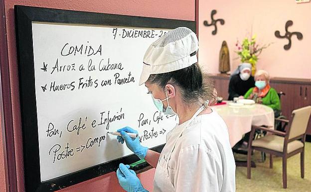 Una cocinera planifica el menú. Al fondo, Goyi y Sor María Jesús.