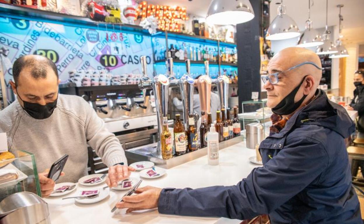 Un cliente muestra su pase covid a un hostelero en Bilbao. 