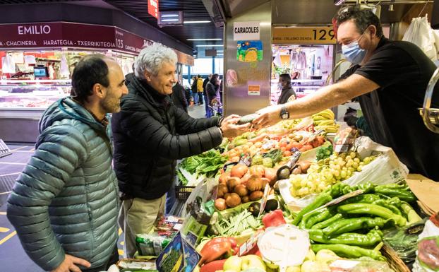 Fernando Canales y Mikel Población compran la verdura en un puesto del mercado bilbaíno.